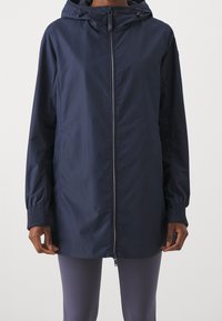 Marinblå lätt jacka med dragkedja framtill, huva och elastiska ärmslut. Slät textur, midjehöjd och minimalistisk design.