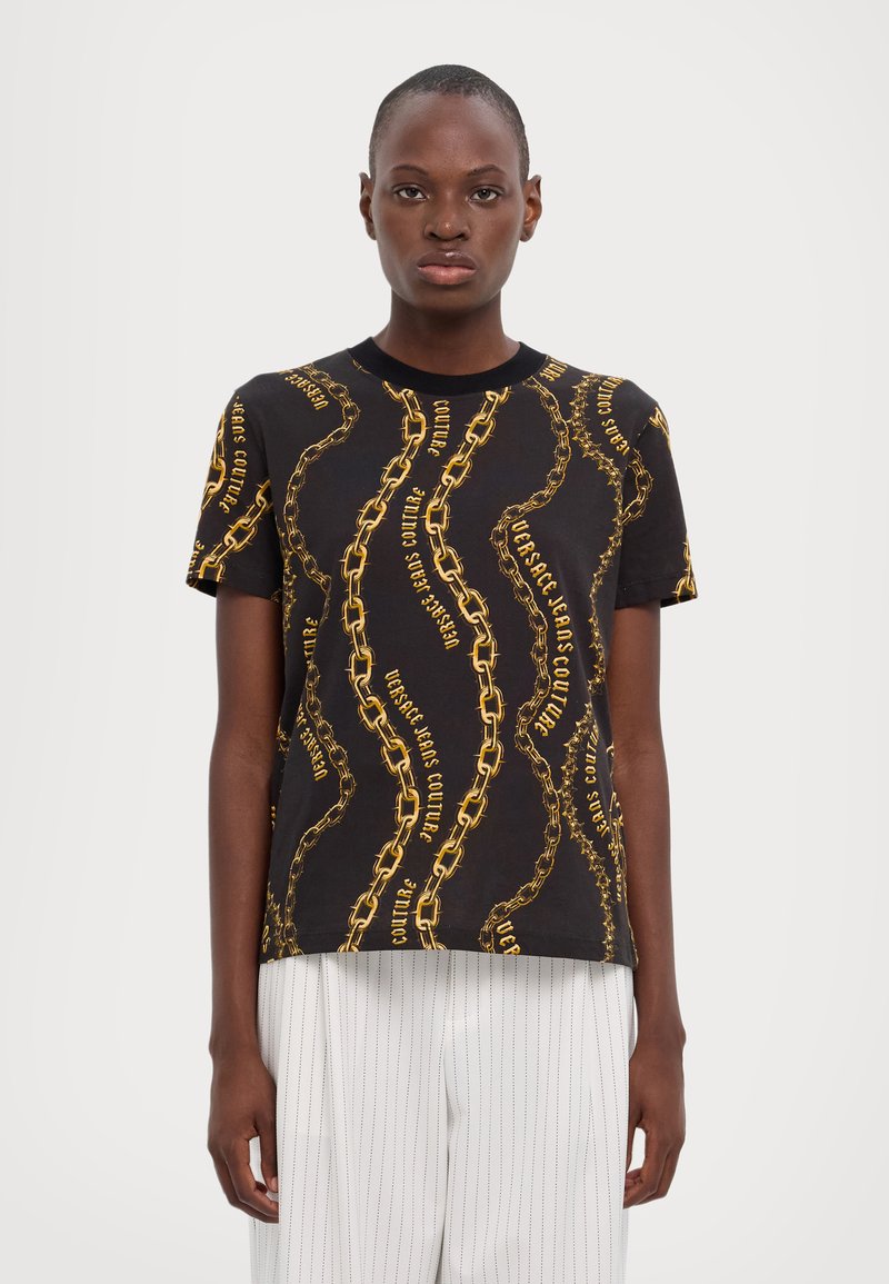 Camiseta de manga corta negra con un patrón de cadenas doradas y el texto "Versace Jeans Couture", fabricada con un tejido suave y de corte relajado.