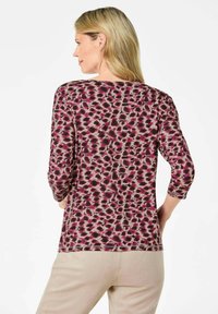 Dreiviertel-Ärmel-Oberteil in einem lebhaften pinken und lila gepunkteten Muster. Weicher Stoff mit einem lässigen Schnitt, rundem Halsausschnitt und Saumdetails.