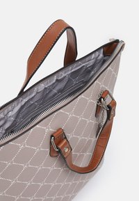 Sac à main à motifs beiges avec des poignées en cuir marron, fermeture zip, et intérieur doublé présentant un design géométrique.