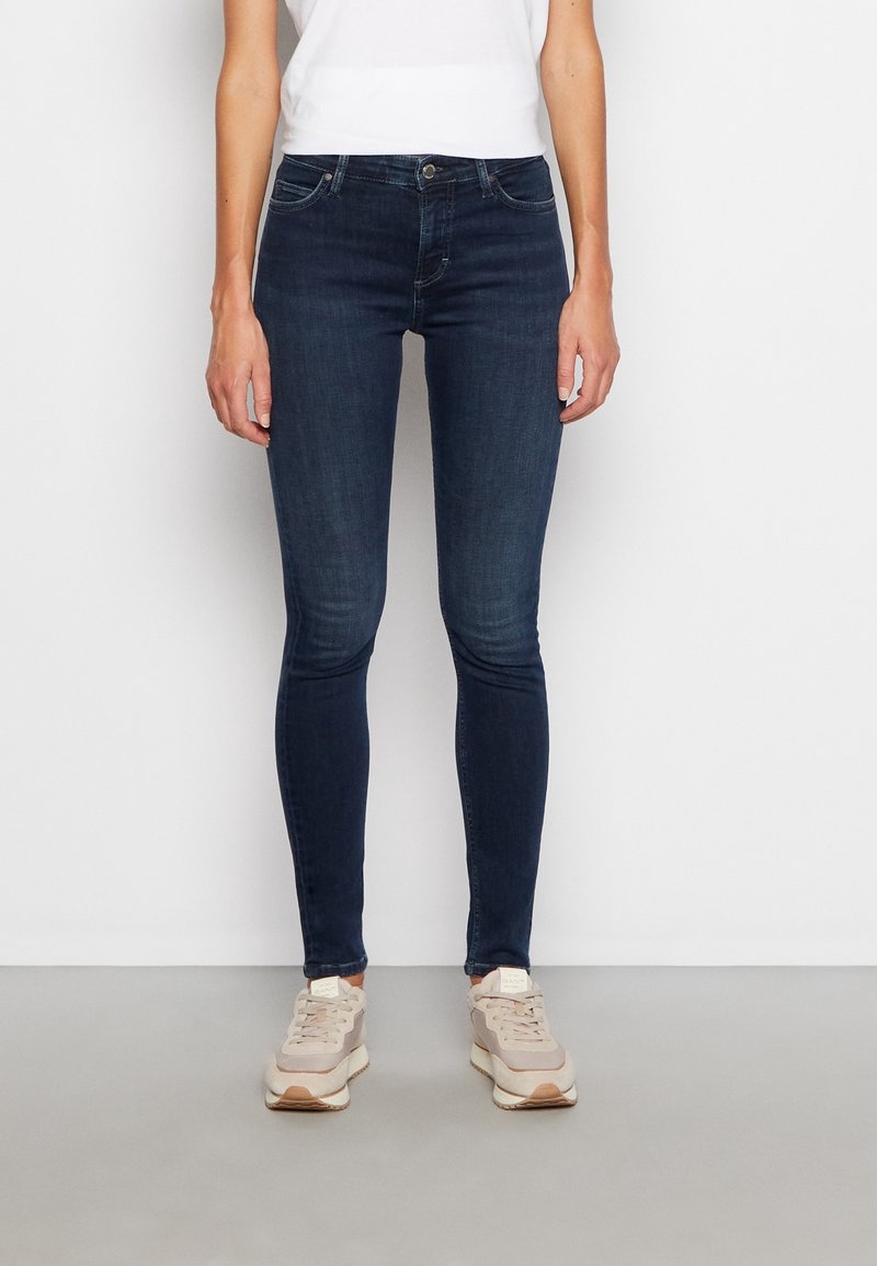 Jeans skinny blu scuro con una texture in denim liscia e leggermente elasticizzata. Design a cinque tasche e chiusura con bottone classica in vita.