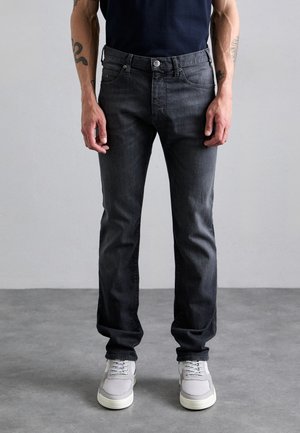 Dark grey denim jeans with a straight-leg fit, five pockets, metal button closure, and subtle fading. Worn with grey mesh sneakers.