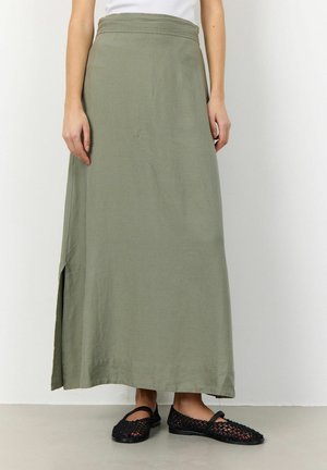 Gonna maxi verde oliva, vestibilità dritta, con spacco laterale, tessuto leggero. Abbinata a scarpe flat nere intrecciate.