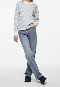 Pasiasta biała i niebieska koszula z długim rękawem, w połączeniu z jasnoniebieskimi dżinsami i czarnymi butami. Swobodny fason z mankietami i dżinsami o prostym kroju.