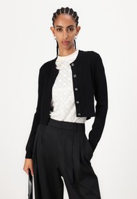 Must have must have must have must have must have must have must have this entry-level, low-key cardigan is made of a soft, warm wool blend and features a round neckline, ribbed edges and five glossy buttons. Perfect for a casual but chic layered look, it's styled over an eye-catching white patterned shirt and sleek black trousers.