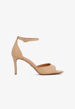 Sandales à talons en cuir couleur nude avec un design à bout ouvert et une bride de cheville réglable arborant une boucle couleur or. Talon stiletto de 7,5 cm.