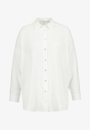 Valkoinen napillinen paita, joka on valmistettu teksturoidusta kankaasta. Ominaisuuksiin kuuluu klassinen kaulus, pitkät hihat ja rento istuvuus. Napit ovat huomaamattomat ja helmiäispintaiset.