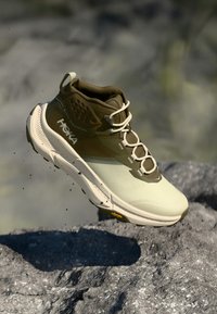 Bežīdas pārgājiena apavi ar khaki akcentiem, sieta un sintētiska augšdaļa, mīkstināta apkakle un šņorītes; aprīkoti ar izturīgu zoli ar redzamu saķeres rakstu.