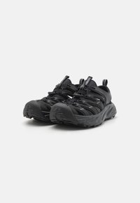 Czarne buty sportowe z teksturowaną cholewką, elastycznym systemem sznurowania i wytrzymałą podeszwą. Oferują wygodny, oddychający design do użytku na świeżym powietrzu.