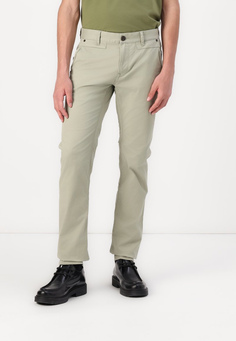 Hellgrüne Baumwollhose mit geradem Bein. Verfügt über frontale Taschen, Gürtelschlaufen und einen Knopfverschluss. Kombiniert mit schwarzen Schuhen.