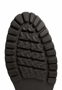 Suela de zapato de goma negra con textura estriada, que presenta patrones rectangulares y en diamante en relieve para una mejor tracción.