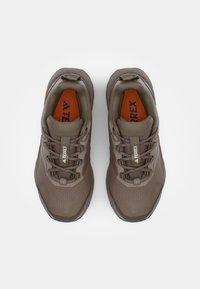 Braune Sportschuhe mit Mesh-Obermaterial, Schnürdesign, gepolstertem Kragen und kontrastierender orangener Einlegesohle. Verfügt über Logodetails und eine strukturierte Sohle.