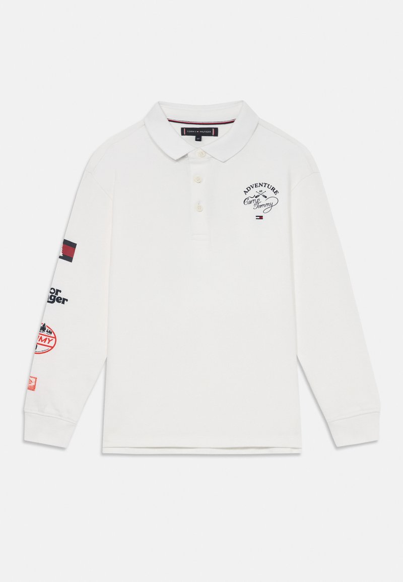 Chemise polo blanche à manches longues avec col, ornée d'accents et de patchs brodés bleu marine et rouge sur les manches. Tissu en coton, coupe décontractée.