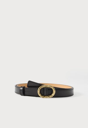 Ceinture en cuir noir avec doublure beige, bords cousus et grande boucle ovale dorée, enroulée sur une surface blanche.