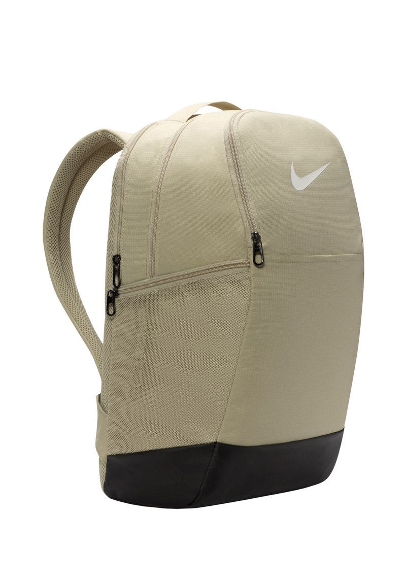 Beige ryggsäck med en texturerad kropp, svart botten, släta dragkedjor och en vit Nike swoosh-logotyp framtill. Justerbara nätremmar ingår.