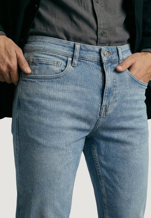 Jean en denim bleu clair avec une coupe droite et une finition délavée. Comprend un design à cinq poches et une fermeture à boutons.