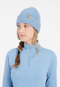 Berretto di maglia azzurro chiaro con un motivo testurizzato, dotato di risvolto e di un piccolo etichetta in tessuto naturale. Materiale morbido.
