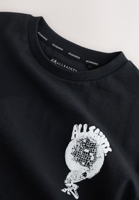 Fekete, pamutból készült kerek nyakú póló. Fehér grafikával díszített, amely egy diszkógömböt tartó csontvázat ábrázol, felette az „ALLSAINTS” felirattal.