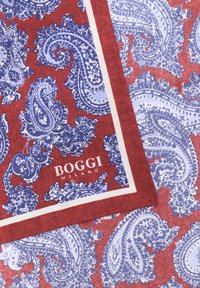 Rdeče in modro vzorčasto blago s paisley motivom, z belim robom in belim besedilom "Boggi Milano" blizu kota.