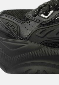 Baskets noires avec une tige en mesh texturé et des accents en cuir lisse. Semelle en caoutchouc épaisse au design ondulé avec le logo "BUFFALO".
