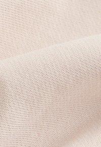 Tela de un suave color rosa claro con una trama fina y texturizada. La superficie parece lisa con sutiles variaciones en grosor y color.