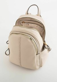 Mochila de cuero beige con cremalleras doradas, que presenta un detalle de diseño trenzado en la parte trasera, dos bolsillos exteriores y correas ajustables.