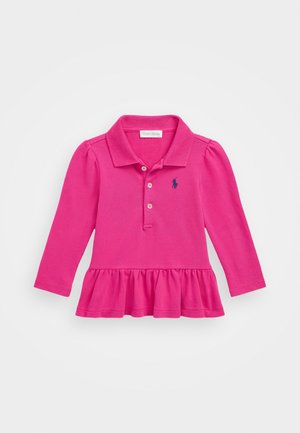 Różowa koszulka polo z długim rękawem, wykonana z fakturowanej tkaniny, ma falbaniasty dół, zapięcie na trzy guziki oraz haftowane logo na wysokości klatki piersiowej.