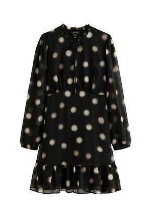 Black dress made of lightweight fabric, featuring a round neckline, long sleeves, and a tiered hem with white polka dots. Tie detail at neckline.