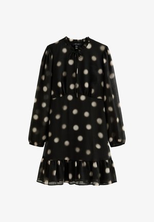 Black dress made of lightweight fabric, featuring a round neckline, long sleeves, and a tiered hem with white polka dots. Tie detail at neckline.