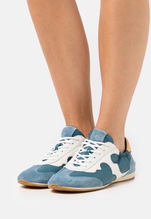 Baskets bleu clair et blanches en matériau suédé et cuir, avec un design à motif superposé et une semelle en caoutchouc beige.