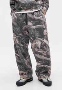 Camo-mønstrede sweats i nuancer af grå og dæmpede jordfarver, med en løs pasform og samlet talje for komfort.