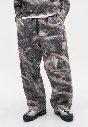 Camo-patterned sweatpants in shades of grey and muted earth tones, featuring a loose fit and gathered waistband for comfort.