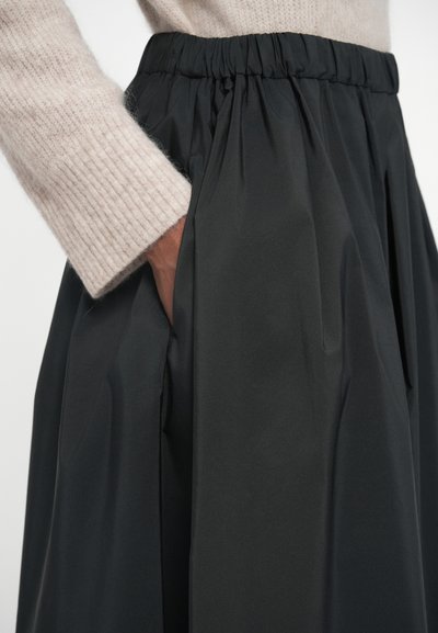 Sorte nederdel med en samlet elastisk talje, lavet af glat stof. Har sidelommer og et flydende design, der viser subtile teksturer.