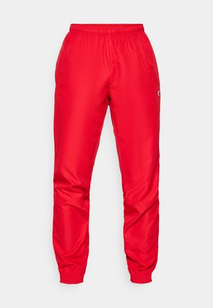 Pantaloni sportivi rossi realizzati in poliester liscia, dotati di vita e polsini elasticizzati, con un piccolo logo sul lato.