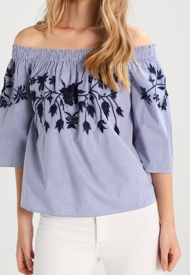 Haut décolleté en rayures bleu et blanc avec broderie florale navy. Caractéristiques : manches 3/4 et encolure élastiquée.