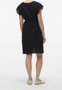 Černé lněné šaty s krajkovými cap sleeve, se staženým pasem a délkou ke kolenům. Nosené s žlutými nazouvacími botami.