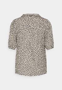 Blusa a maniche corte in crema con motivo floreale nero. Presenta un colletto, un retro plissettato e una vestibilità rilassata. Tessuto leggero.