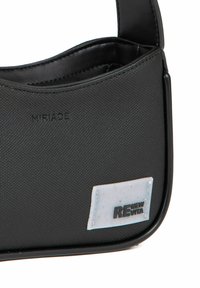 Sorte crossover taske lavet af struktureret materiale, med en glat rem, prægede logo og et geometrisk patch med "RENEW VITA."