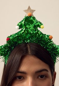 Green sequined Christmas tree headband with tinsel, topped with a gold star, featuring colored pom-poms in yellow, red, and white accents.