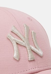 Pink baseball cap featuring a large, metallic silver embroidered 'NY' logo. The textured fabric has visible stitching details.