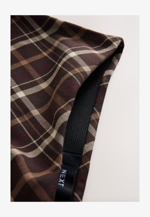 Ruskeaa ruudullista kangasta, jossa valkoisia ja beigejä viivoja, sileällä pinnalla ja musta joustava nauha ommeltuna reunaa pitkin.