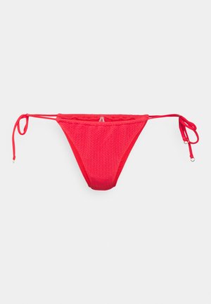 Sarkans bikini apakšda ar teksturētu, adītu rakstu. Aprīkota ar regulējamiem sānu saišu mezgliem un augstu izgriezumu. Nav papildu rotājumu.