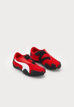 Røde atletiske sko med en sort gummisål, der har et design med hvide striber og justerbare remme over skaftet. Struktureret, fleksibelt materiale.