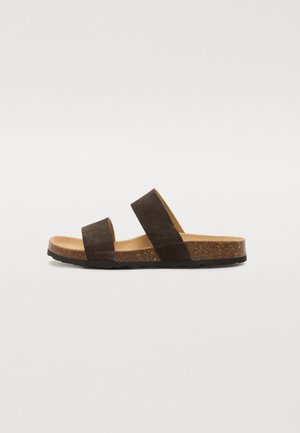 Sandales glissantes en suède marron avec deux larges brides, semelle intérieure en liège naturel et semelle extérieure en caoutchouc texturé, dotées d'un design plat et minimaliste.