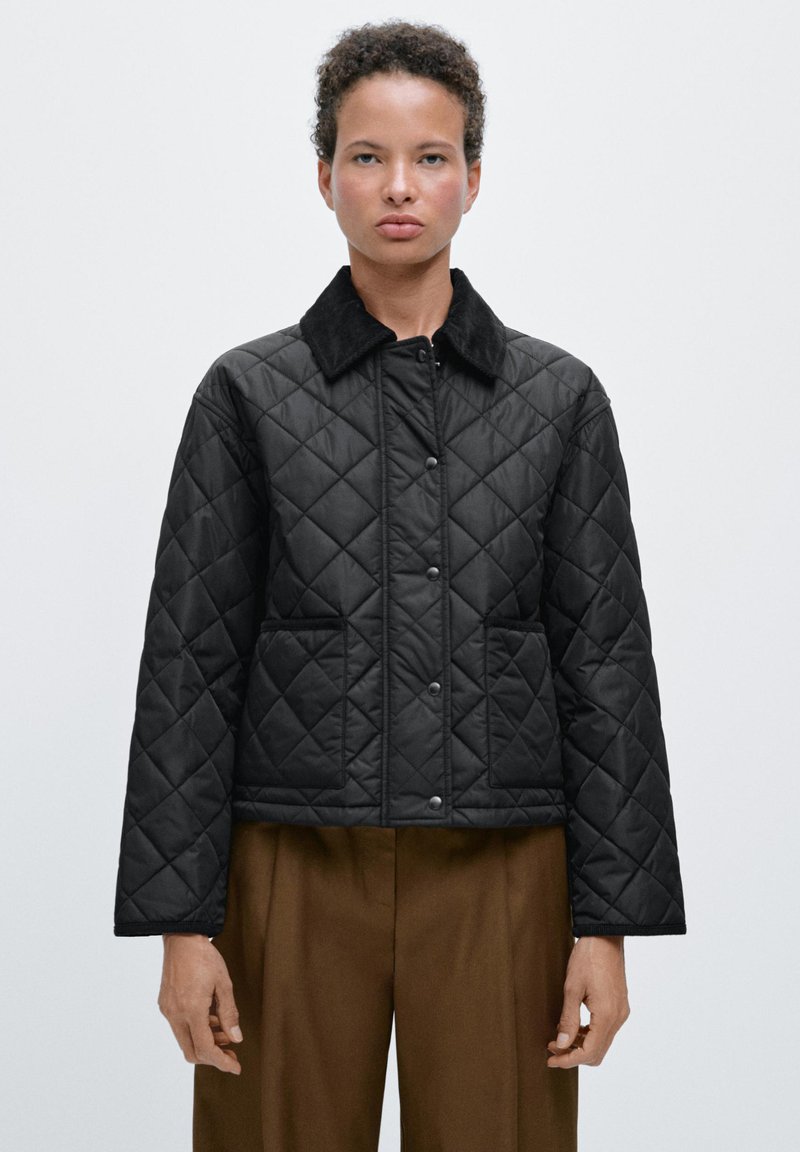 Zwarte gewatteerde jas met een kraag, voorzien van een ruitpatroon, voorzakken en drukknoopsluitingen. De mouwen zijn iets oversized.