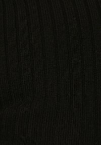 Nära bild av svart ribbad stickad tyg med vertikala texturerade linjer.