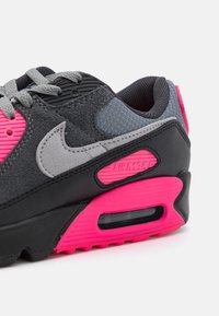 Nike Air Max-sneaker med svart og grå overdel, rosa detaljer, teksturerte materialer, synlig Air-enhet og kontrasterende snøresystem.