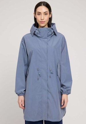 Woman wearing a mid-length blue hooded raincoat with elastic cuffs and adjustable waist drawstrings, standing against a plain background.
