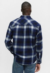 Karierte Flanellhemd mit marineblauen, grauen und weißen Mustern. Lange Ärmel, Knopfmanschetten und ein klassisches Kragenmuster.