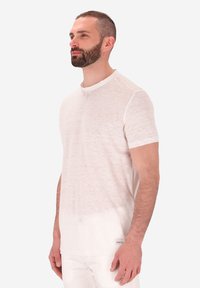 T-shirt bianco a maniche corte realizzato in tessuto leggero e textured. Presenta un collo rotondo e una piccola etichetta con logo sull'orlo.